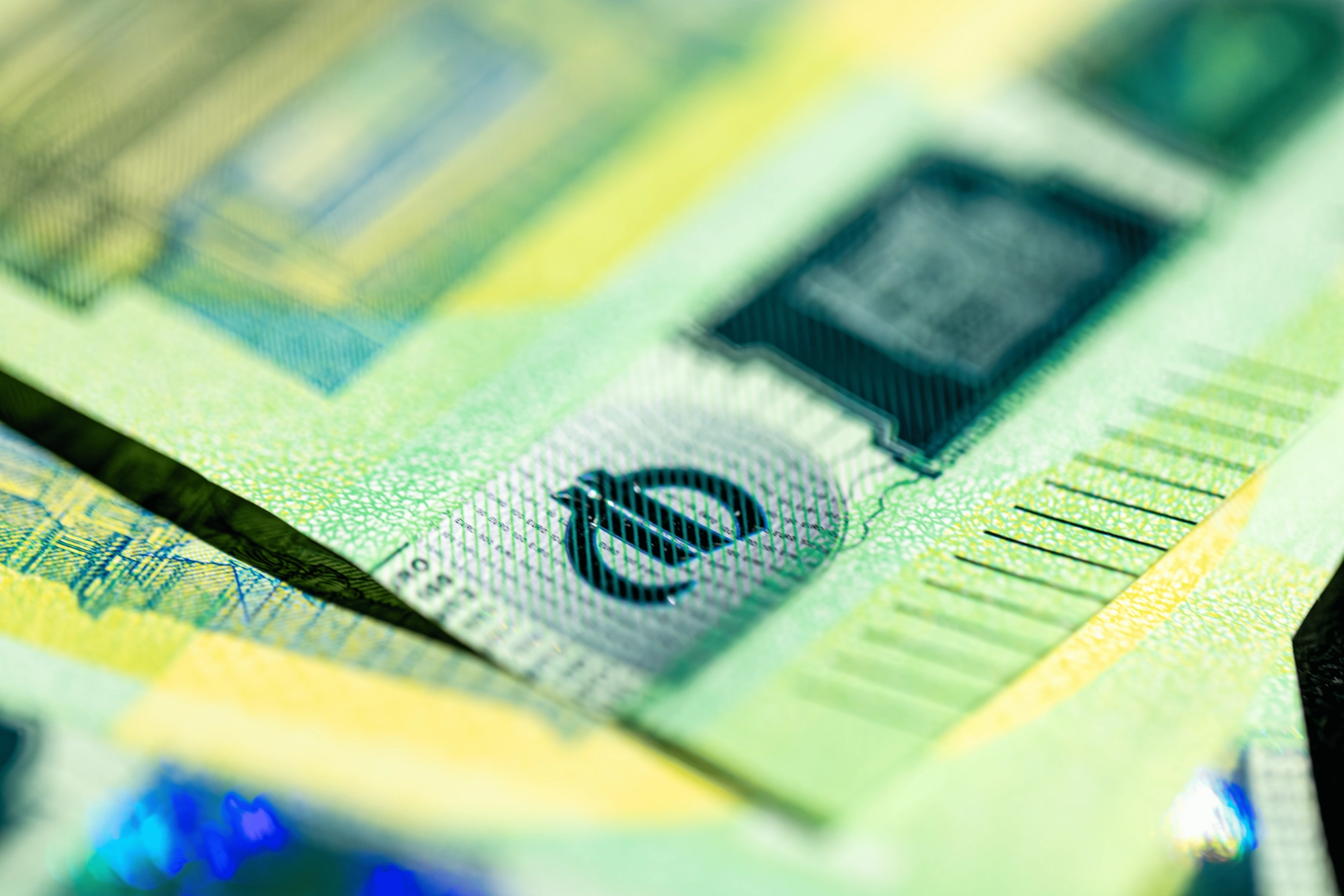 Detalhe ampliado de uma nota de Euro destacando o símbolo da moeda europeia em foco